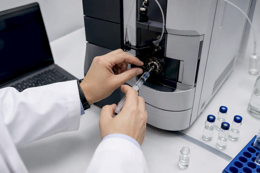 Hands injecting sample in lab instrument